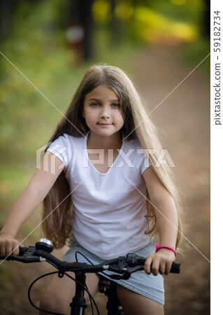 Little girl having fun on bike in the forest in autumn season Little girl having fun on bike in the forest in autumn season 59182734
