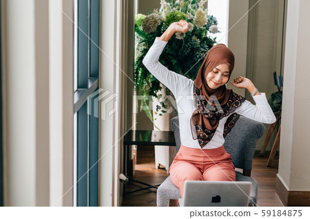 Muslim female with laptop stretching body Muslim female with laptop stretching body 59184875
