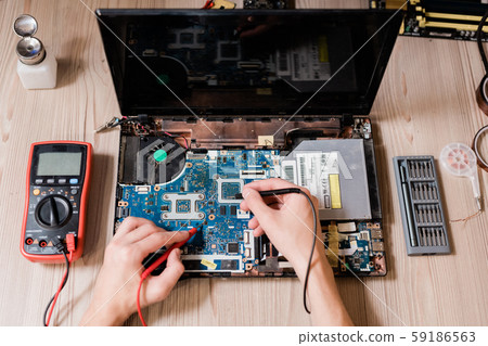 Hands of contemporary master using small soldering-irons to repair broken laptop 59186563
