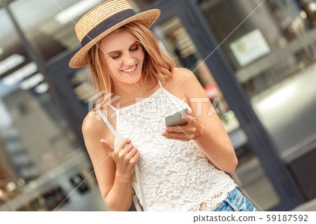 Traveler. Young woman in hat standing on street browsing smartphone smiling joyful Traveler. Young woman in hat standing on street browsing smartphone smiling joyful 59187592