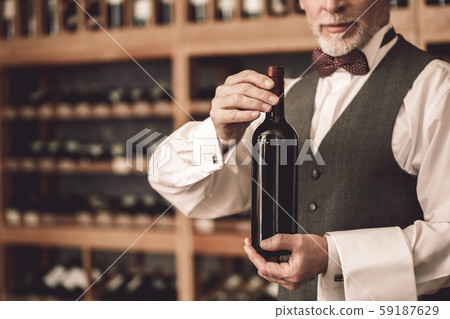 Sommelier Concept. Senior man standing showing botle of wine friendly close-up 59187629