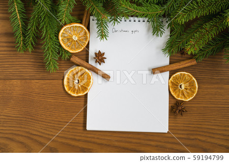 Flat lay christmas gift list notepad with spruce twigs and decorations on ash wood surface Flat lay christmas gift list notepad with spruce twigs and decorations on ash wood surface 59194799