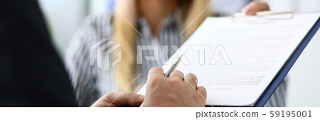 Smiling female real estate agent offering male visitor document to sign Smiling female real estate agent offering male visitor document to sign 59195001