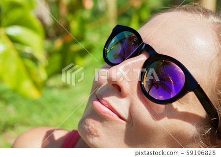 Woman wearing sunglasses with palms, sky 59196828