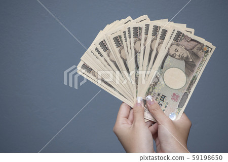 Close up female hand holding Japanese yen 10000 banknotes 59198650