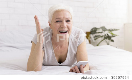 Excited senior woman enjoying win, reading message on smartphone 59207934