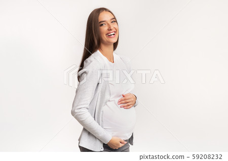 Happy Pregnant Woman Touching Belly And Laughing In Studio Happy Pregnant Woman Touching Belly And Laughing In Studio 59208232