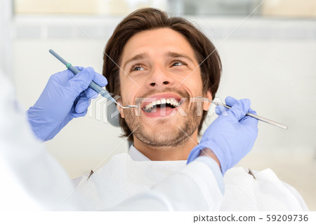 Portrait of handsome smiling man attending dentist 59209736