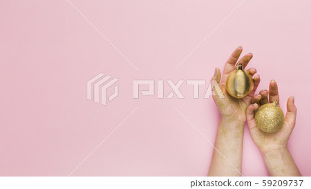 Woman holding gold decoration balls in hands on pink 59209737