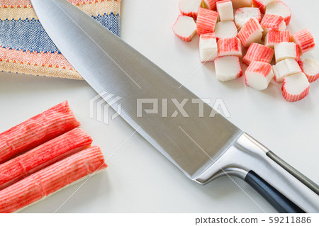 Whole and sliced surimi crab sticks and sharp chef knife on a white kitchen table. 59211886