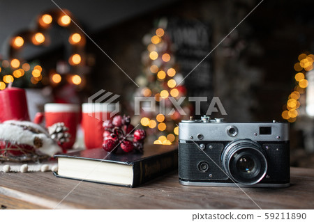 Retro camera is on the table on the background of Christmas songs and Christmas trees Retro camera is on the table on the background of Christmas songs and Christmas trees 59211890