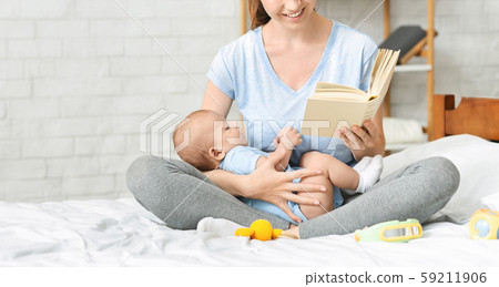 Happy mother reading book to her toddler at home 59211906