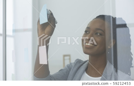 Businesswoman Reading Colorful Notes On Glass Board In Office Businesswoman Reading Colorful Notes On Glass Board In Office 59212453