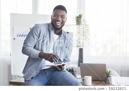 Cheerful black employee using digital tablet in office and laughing 59212621