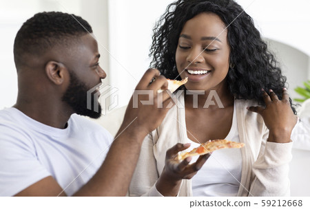 Young black couple sharing pizza on date at home 59212668
