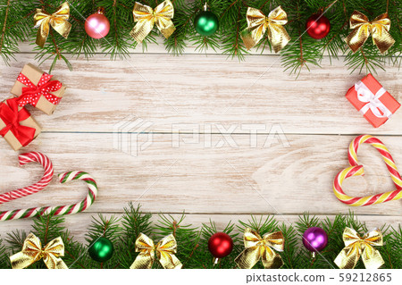 Christmas frame made of fir branches decorated with balls, bows, candy canes and boxes on a light 59212865