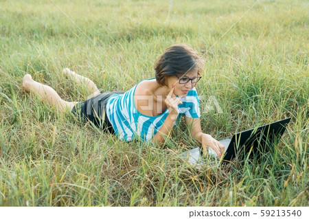 woman with glasses using computer laptop on grass. Female blogger, freelancer working in nature woman with glasses using computer laptop on grass. Female blogger, freelancer working in nature 59213540