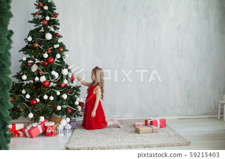 Little girl opens gifts at Christmas tree new year winter Little girl opens gifts at Christmas tree new year winter 59215403