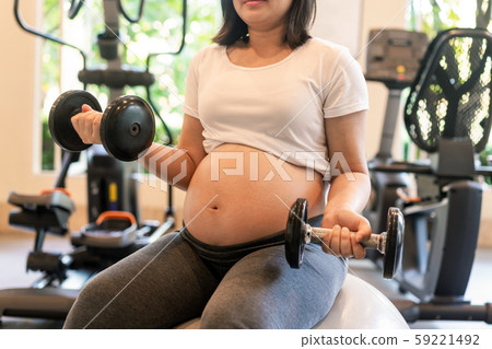 Active pregnant woman exercise in fitness center. Active pregnant woman exercise in fitness center. 59221492