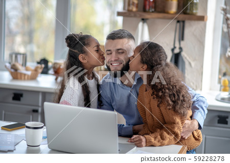 Girls kissing their daddy while feeling happy together 59228278