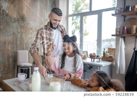 Bearded beaming father feeling happy cooking with children 59228639