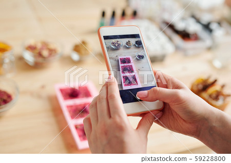 Hands of girl with smartphone taking photo of handmade soap in silicone molds 59228800