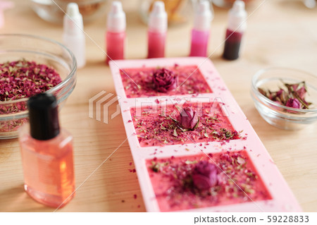 Silicone molds filled with handmade pink soap sprinkled by grated floral petals 59228833