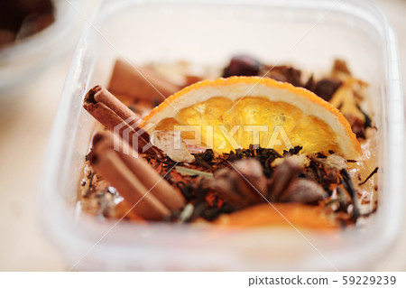 Fresh orange slice, cinnamon sticks and grated dry spices in liquid soap mass 59229239