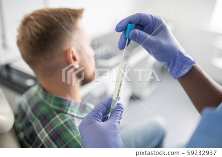Gloved doctor holding small dropper and keeping it in flask with medicine Gloved doctor holding small dropper and keeping it in flask with medicine 59232937