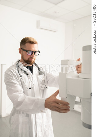 Bearded young man in whitecoat checking new medical equipment in clinics 59233400
