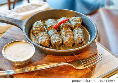 Dolma in a pan on a wooden stand with cutlery, Dolma in a pan on a wooden stand with cutlery, 59245667
