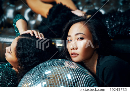 Pretyy women relax and lying down on the floor on disco ball in nightclub after crazy party 59245783
