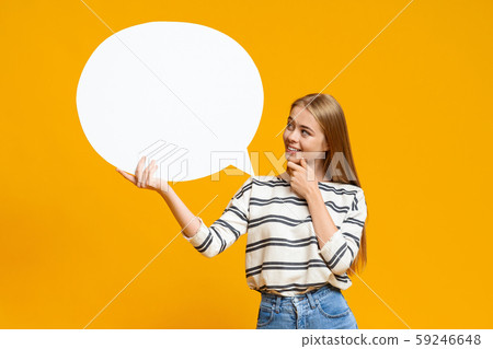 Pensive young girl holding blank speech bubble over yellow background 59246648