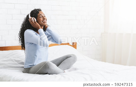 Cheerful young girl listening to music in bedroom Cheerful young girl listening to music in bedroom 59247315