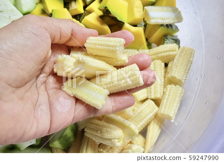Hand Holding Chopped Baby Corns with Sponge Gourds 59247990