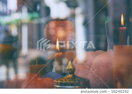 Candles in the shape of pumpkins behind a glass 59248392