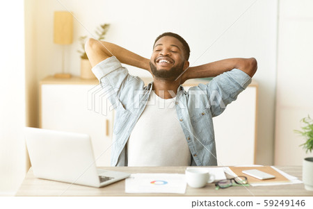 Happy afro worker leaning back in chair after successful workday Happy afro worker leaning back in chair after successful workday 59249146