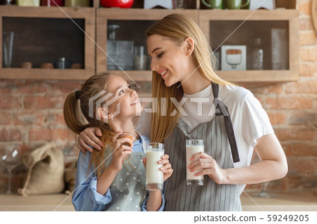 Pretty mom and daughter drinking milk at kitchen 59249205