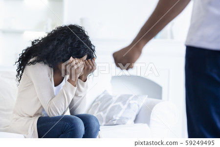 Woman hiding her face from husband's fist, suffering from abuse 59249495