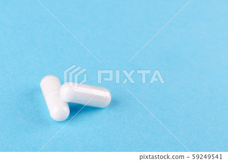 two white capsules of nutritional supplement on blue background with copy space two white capsules of nutritional supplement on blue background with copy space 59249541
