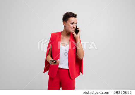 Office woman in red suit talking on the phone with client 59250635