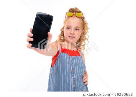 Picture of happy child with fair red curly hair shows a phone isolated on white backround Picture of happy child with fair red curly hair shows a phone isolated on white backround 59250658