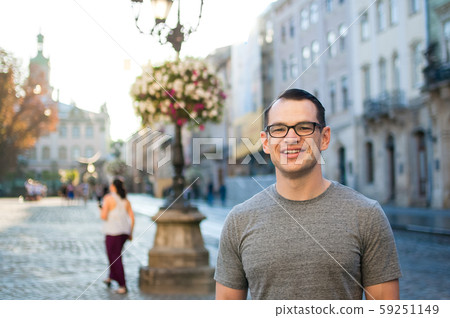 Outdoors portrait of an excited male tourist in the street with buildings of an old town in Europe Outdoors portrait of an excited male tourist in the street with buildings of an old town in Europe 59251149