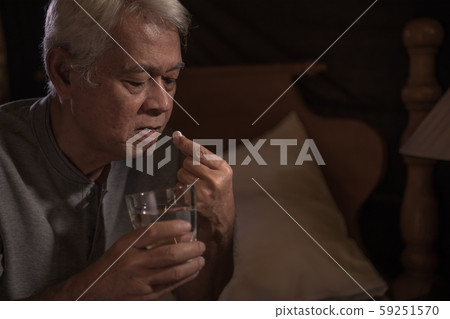 Depressed senior person sitting in bed cannot sleep from insomnia and taking medication 59251570