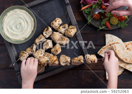 Grilled chicken skewers with hummus and salad 59252063