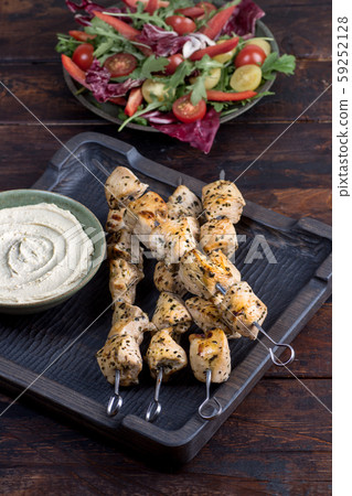 Grilled chicken skewers with hummus and salad 59252128