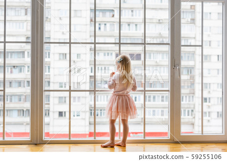 Happy little girl wearing cute dress looking at window 59255106
