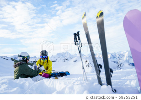 Image of skis, ski poles, snowboard against background of two sports women with thermos sitting in Image of skis, ski poles, snowboard against background of two sports women with thermos sitting in 59255251