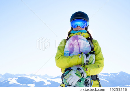 Photo of sportswoman in helmet and goggles with snowboard at ski resort. Photo of sportswoman in helmet and goggles with snowboard at ski resort. 59255256