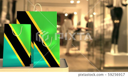 Flag of Tanzania on the paper shopping bags against blurred store entrance. Retail related 3D 59256917